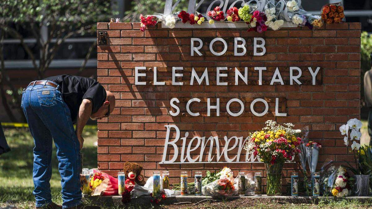 A law enforcement member lights a candle outside Robb Elementary School in Uvalde, Texas, in May 2022.
