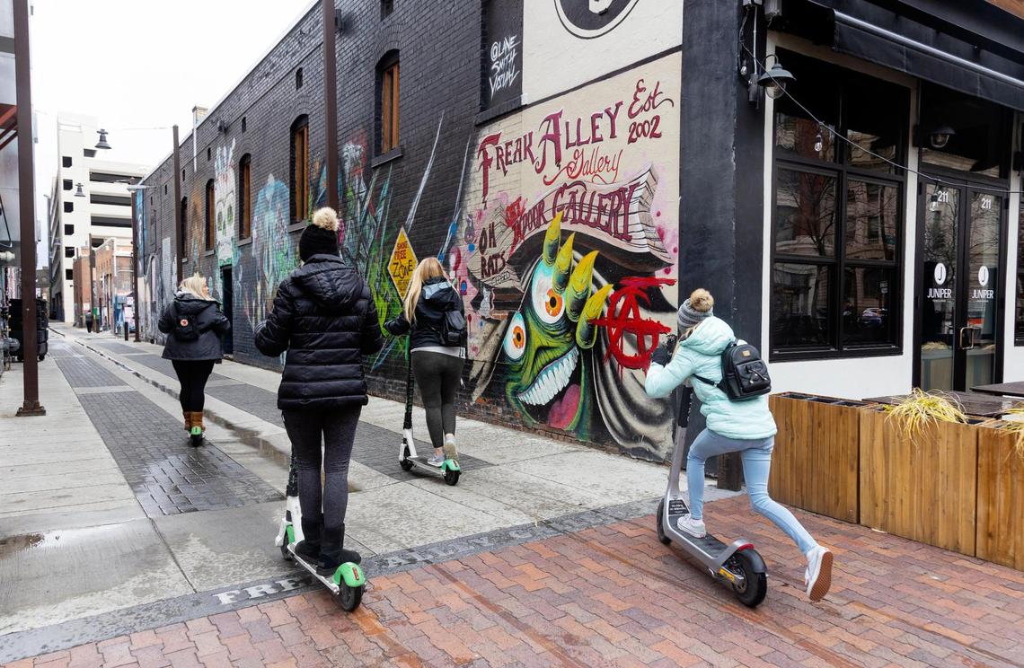 People ride scooters through Freak Alley Gallery in downtown Boise on April 13, 2022. The alleyway, located behind the businesses between 8th Street and 9th Street and Bannock Street and Idaho Street showcases local graffiti style art.