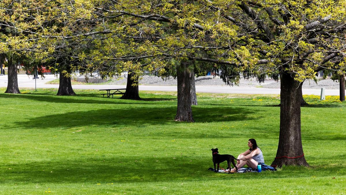A Boise resident enjoys a warm spring day with her dog Sky at Veterans Memorial Park in Boise, May 3, 2023.