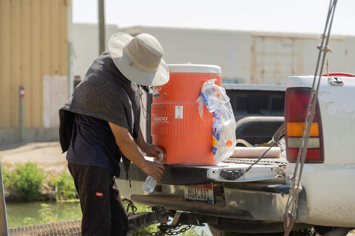 A farmworker filling his bottle with water while working in Wilder