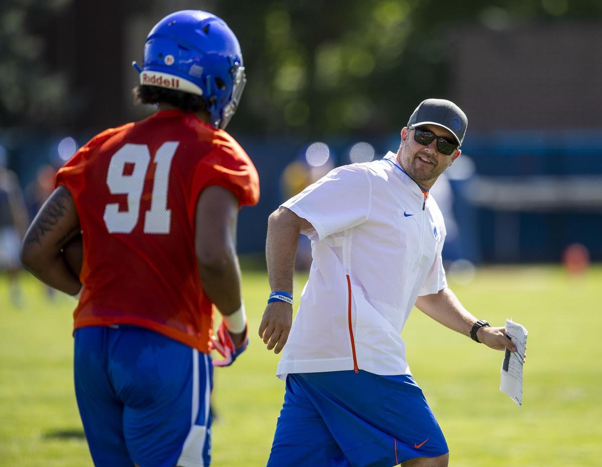 Boise State’s defensive coordinator Jeff Schmedding runs with defensive end Dylan Hall during the afternoon practice Friday, Aug. 2, 2019.