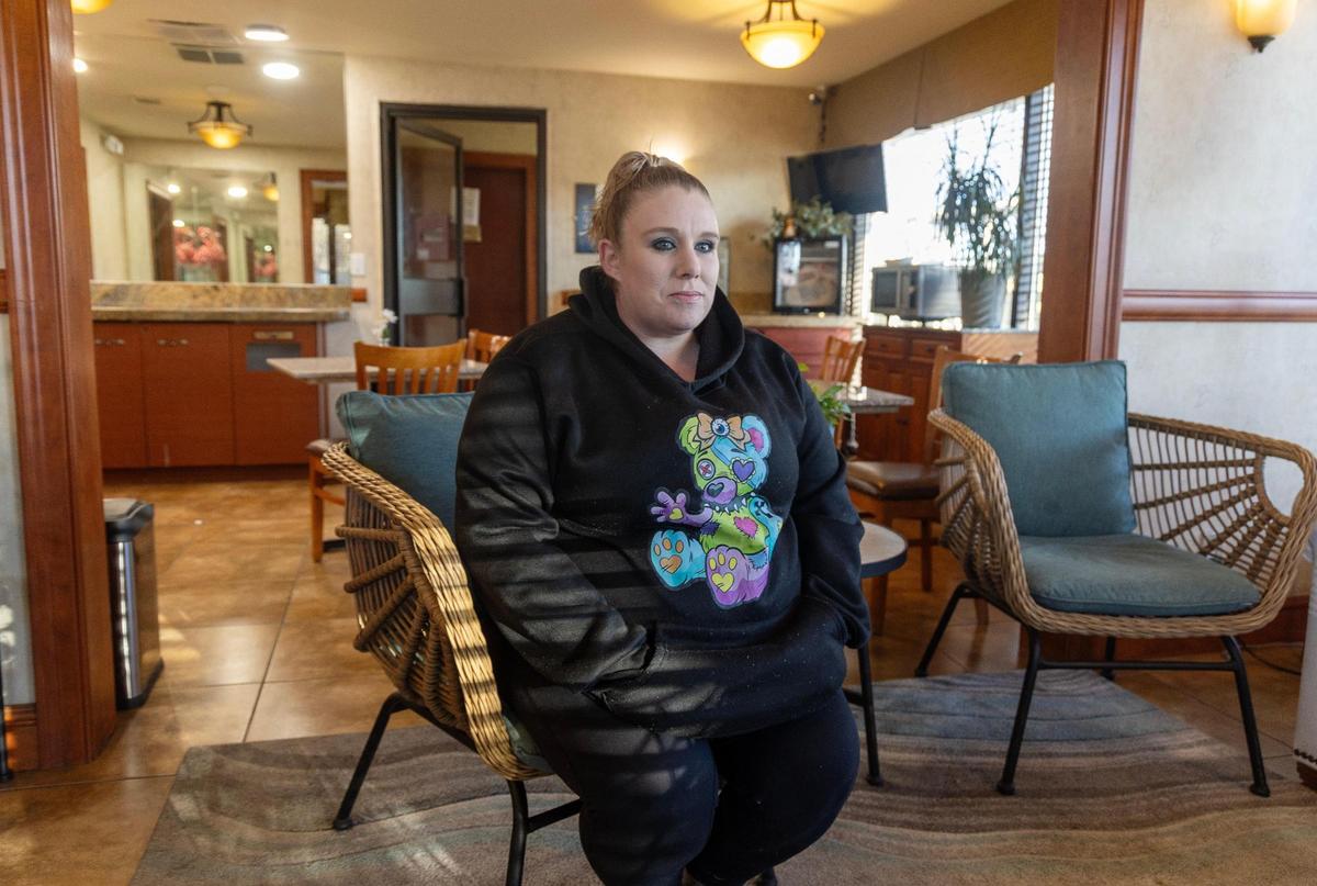 Stormy Robles sits in the lobby of the Airport Inn hotel where she lives and works. Residents of the hotel are being evicted.