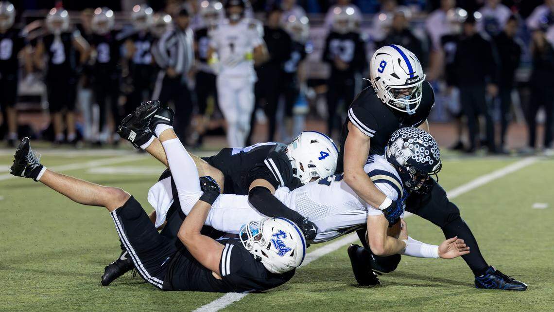 Middleton junior quarterback Briar Baughman is brought down by Timberline senior linebacker Nash O'Kelley, left, senior defensive back Austin Engroff, center, and junior defensive lineman Evan Paschke, right, during the 6A football state quarterfinals, held at Dona Larsen Park, Friday, Nov. 7, 2025.