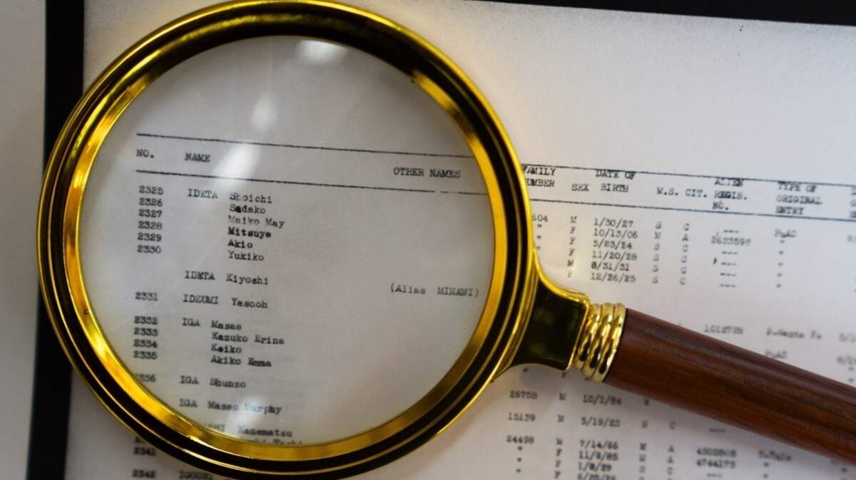 A magnifying glass sits over a page of camp records for Associated Press Photographer Lindsey Wasson’s maternal grandfather Akio Ideta and family, in the visitor center at Minidoka National Historic Site.