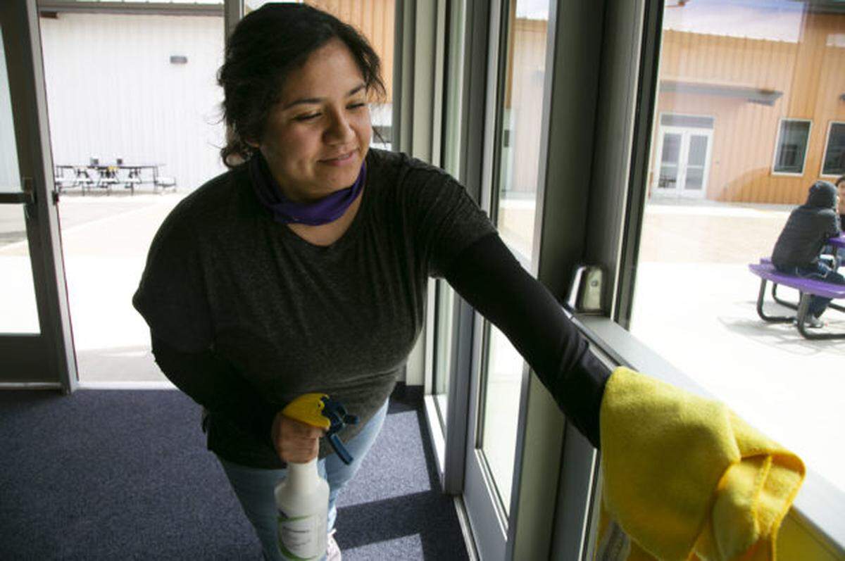 Cinthia Villanueva, who joined the Elevate staff to help during the pandemic, sanitizes doors in the Elevate Academy cafeteria.