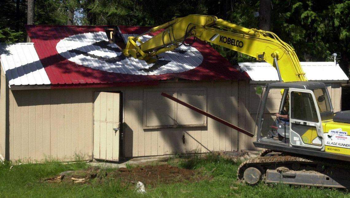 An excavator digs into a dilapidated cook shack at the Aryan Nations compound near Hayden Lake on May 23, 2001. The swastika symbol on the roof is recognizable in multiple scenes in “The Order,” a new movie about a white supremacist terrorist group from the 1980s that had real ties to the Aryan Nations.