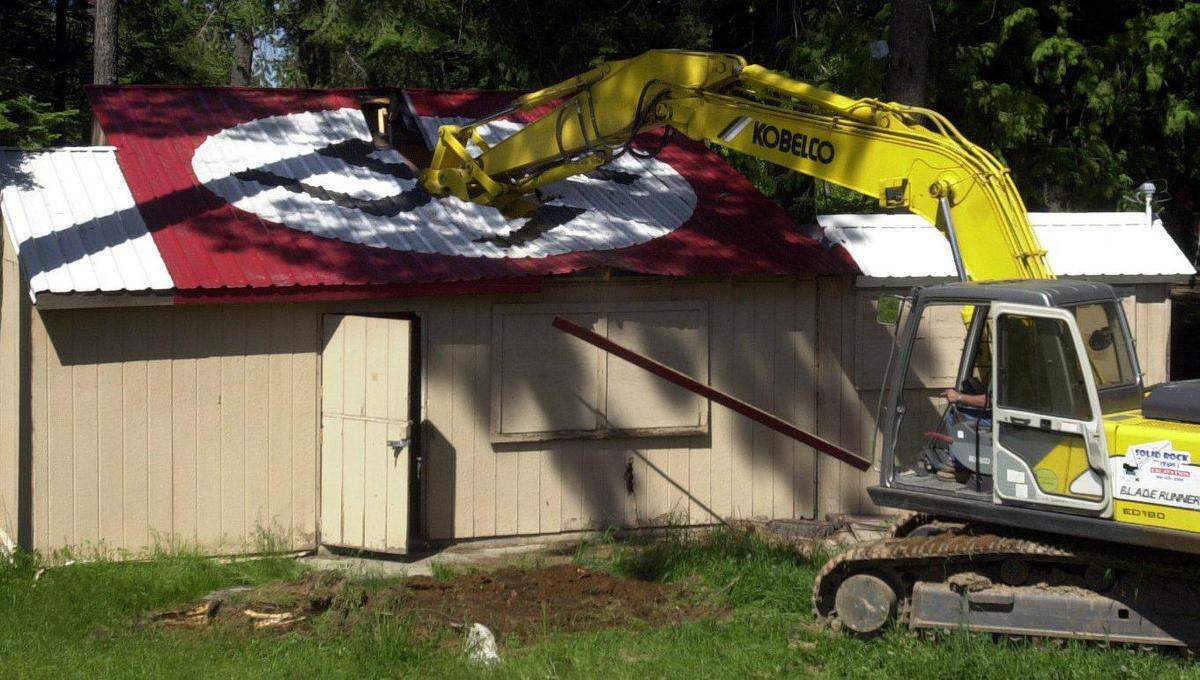 An excavator digs into a dilapidated cook shack at the Aryan Nations compound near Hayden Lake on May 23, 2001. The swastika symbol on the roof is recognizable in multiple scenes in “The Order,” a new movie about a white supremacist terrorist group from the 1980s that had real ties to the Aryan Nations.