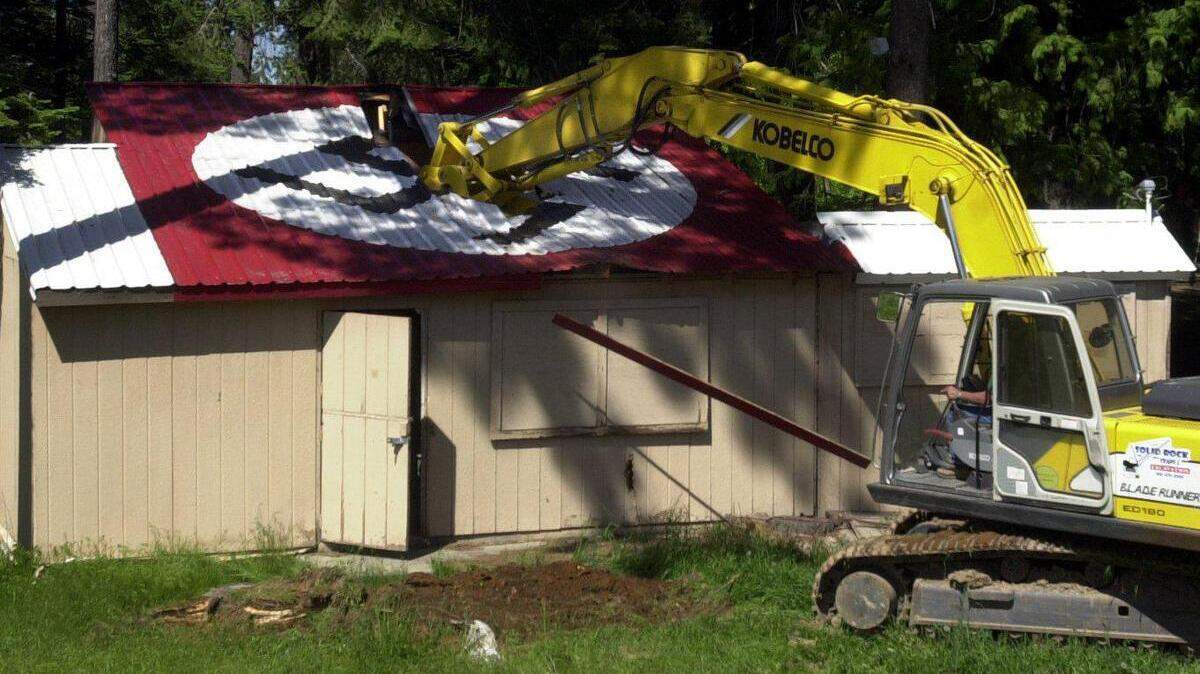 An excavator digs into a dilapidated cook shack at the Aryan Nations compound near Hayden Lake on May 23, 2001.
