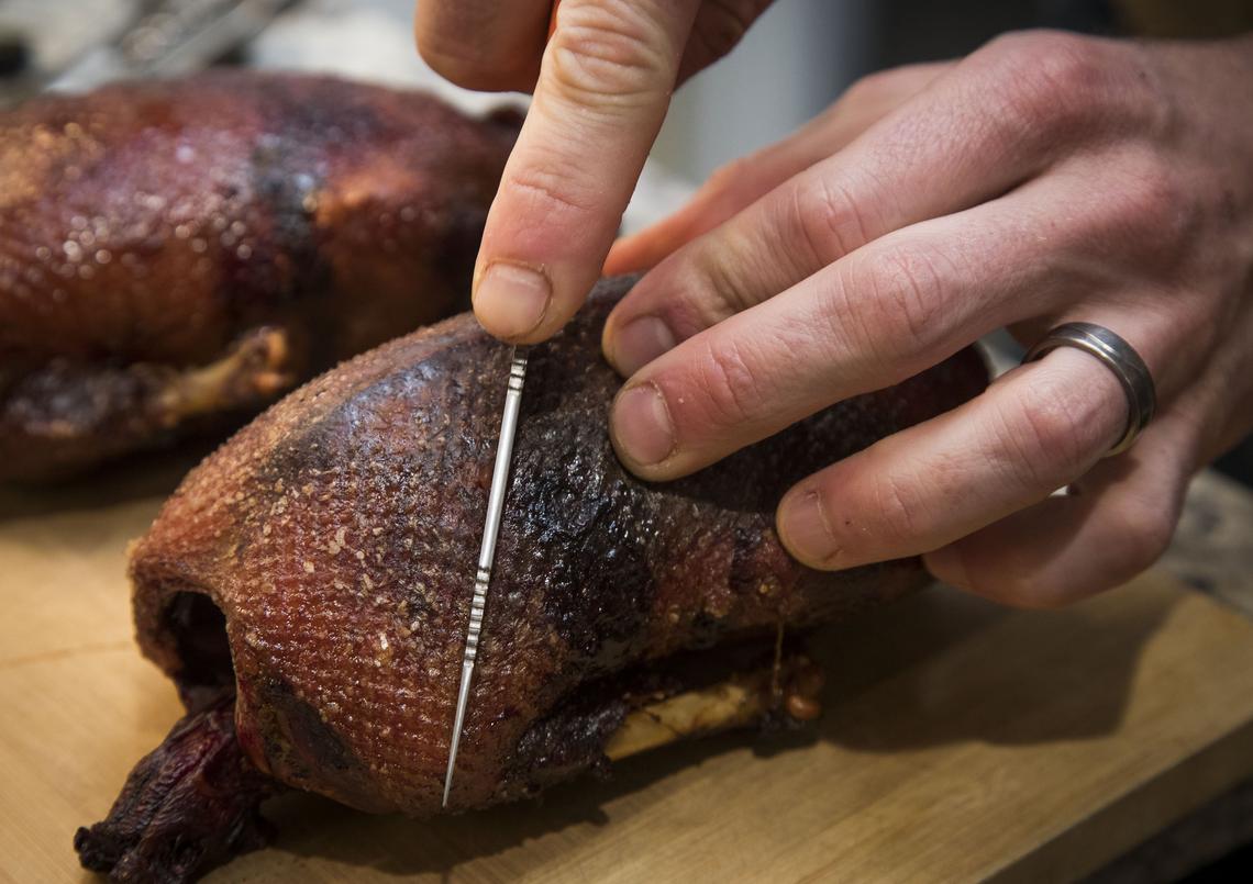 Brined for 24 hours and slow-smoked for six hours, Brad Brooks slices through the crispy skin of Mallard duck breasts from a duck hunt just days earlier. Each duck was coated in maple syrup and salted before cooking for a savory sweet flavor that enhances the wild game.