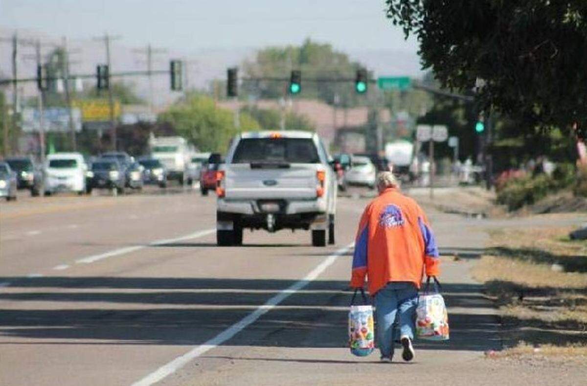 A woman walks on the shoulder of Chinden Boulevard with her grocery bags. A lack of sidewalks on the busy street has led to several Treasure Valley agencies seeking federal money to explore potential improvements to the pedestrian experience.