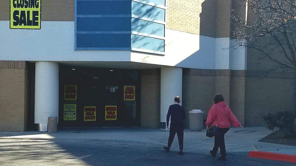 Customers walk Tuesday toward the Sears store in the Boise Towne Square. Signs in the doors advertise the store’s liquidation sale.