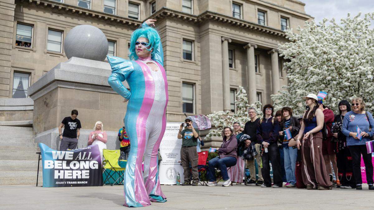 A drag performer wears the colors of the Transgender Pride flag while dancing on the steps of the Idaho Capitol.