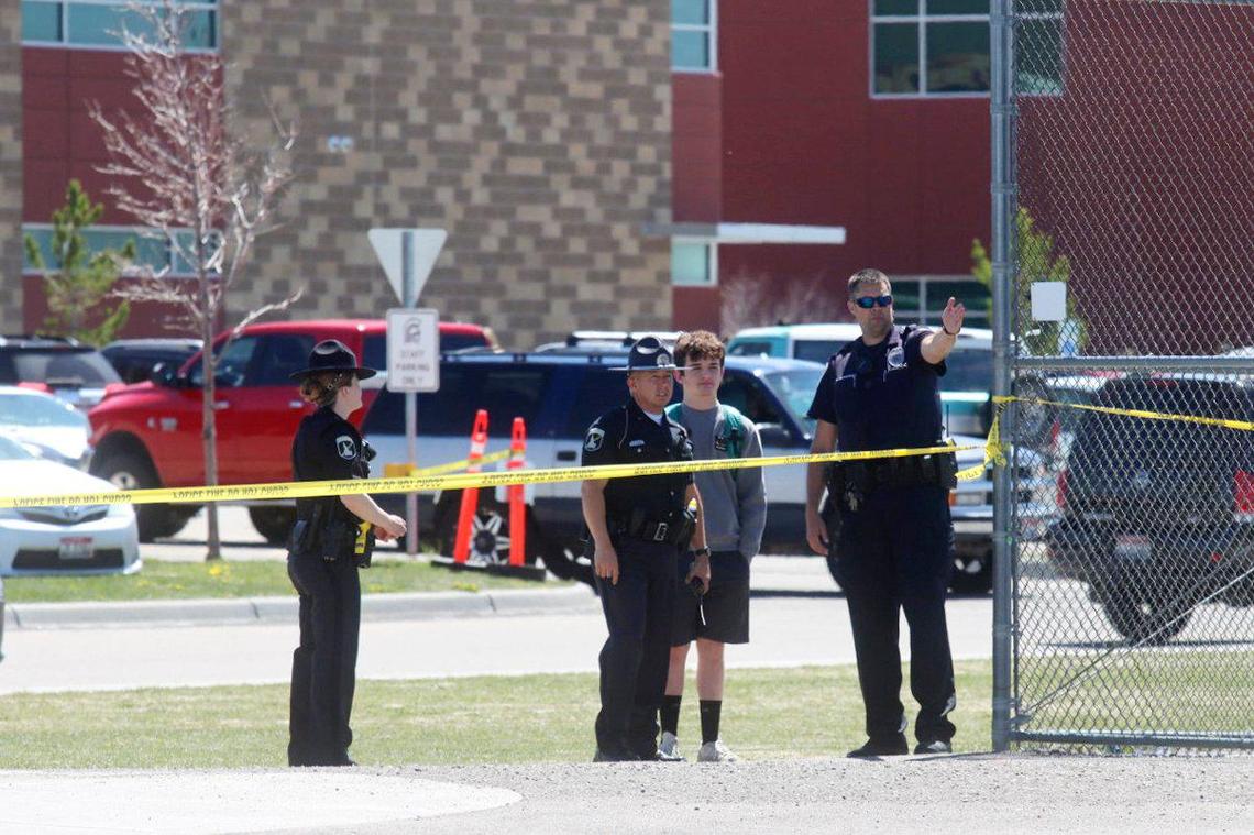 Police stand with a youth outside Rigby Middle School following a shooting there on May 6. Authorities said two students and a custodian were injured.