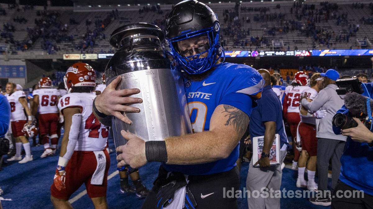 Boise State defensive tackle Scott Matlock hugs the Milk Can trophy after a win over Fresno State in 2022, his senior season.