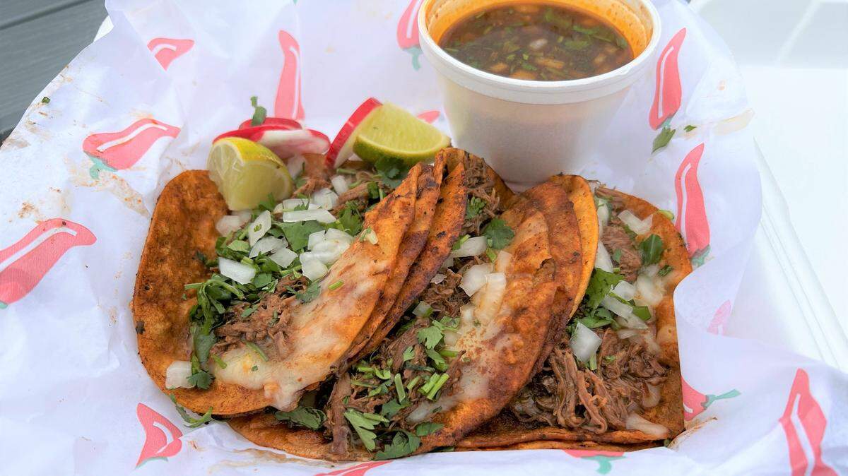 A quesabirria taco plate ($10) comes with three tacos, a side of consome for dipping, plus wedges of lime and radish. Two hot sauces are included on the side.