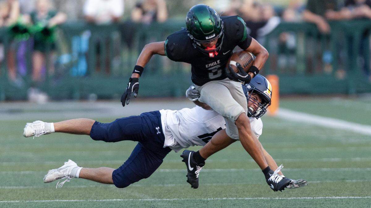 Eagle senior Colin Duarte returns a punt before getting tripped up by Meridian's James DiStefano in 6A SIC football action at Eagle, Friday, Aug. 29, 2025.