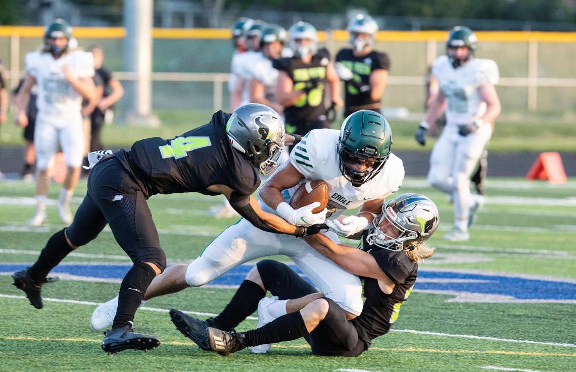 Eagle tight end Donovan Jones is brought down by Mountain View’s Mason Chiles, left, and Hank Wemhoff, right, on Friday at Mountain View.