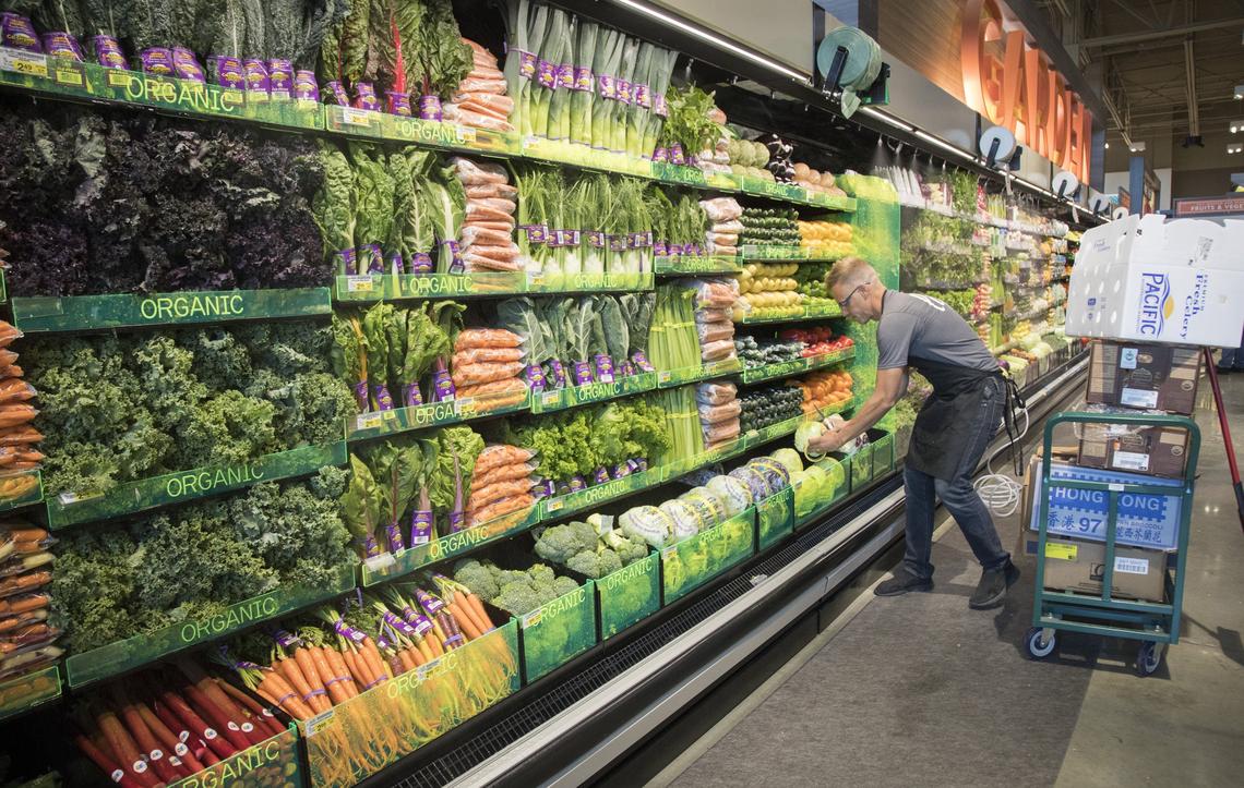 Justin Trujillo adds cabbages to the expanded organic section at the new Albertsons on Broadway Avenue.