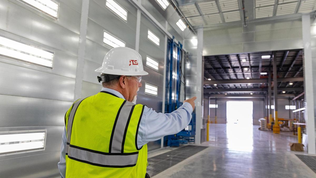 Blake gestures toward the end of the building as he walks through a painting bay in the company’s new plant.