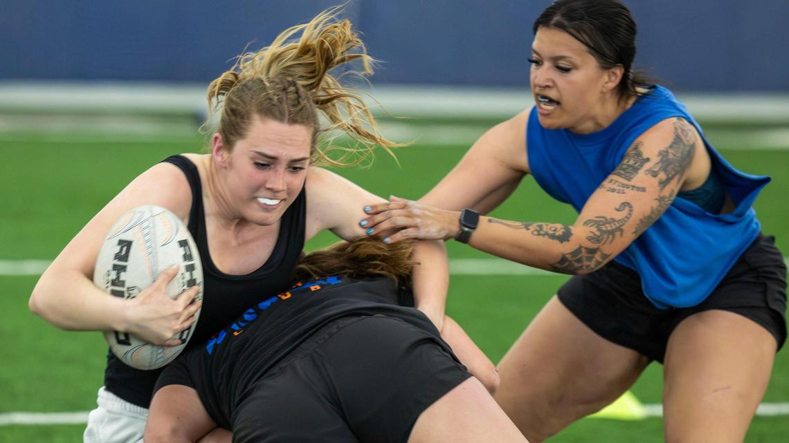 Fly-half Ella Ogletree absorbs a tackle by teammate Briana Fry as teammate Kimber Bevens, right, waits to assist the play during a Boise State women’s rugby practice Wednesday night.
