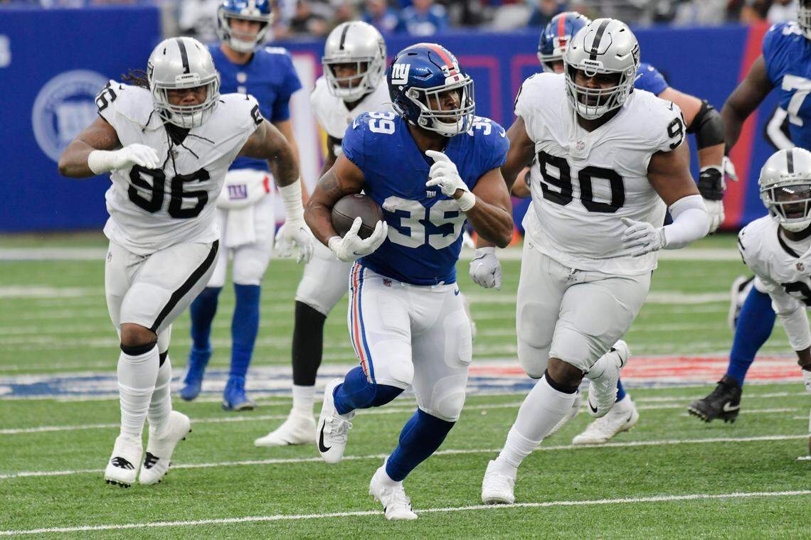 Las Vegas Raiders’ Darius Philon, left, and Johnathan Hankins, right, chase New York Giants’ Elijhaa Penny, center, during the second half of their game Sunday in East Rutherford, N.J.