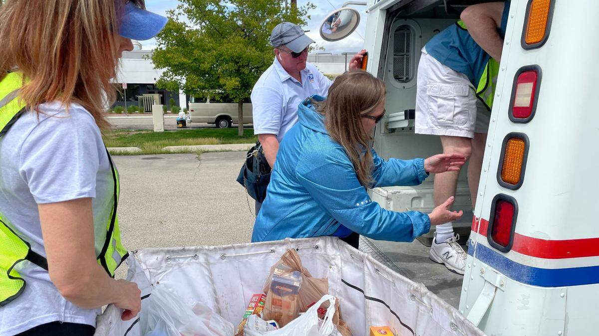 Postal workers work to unload a U.S. Post Office truck full of donated non-perishables.