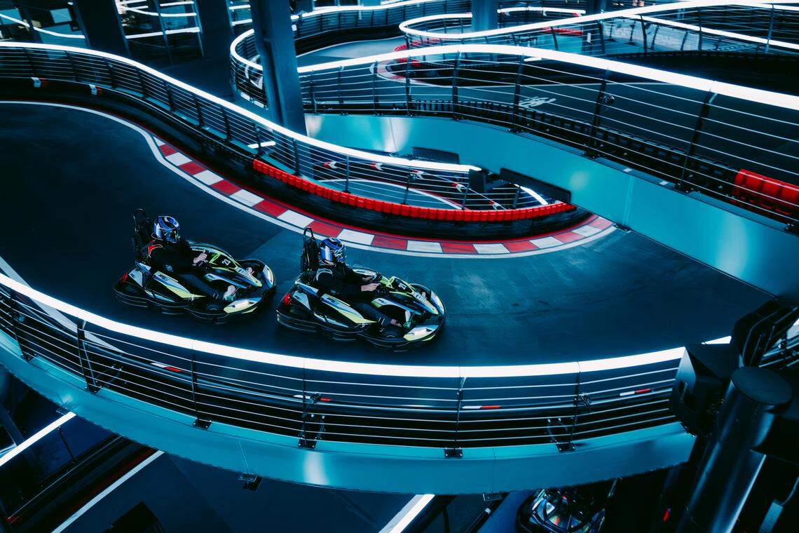 Go-kart drivers navigate curves along elevated tracks manufactured by 360 Karting.
