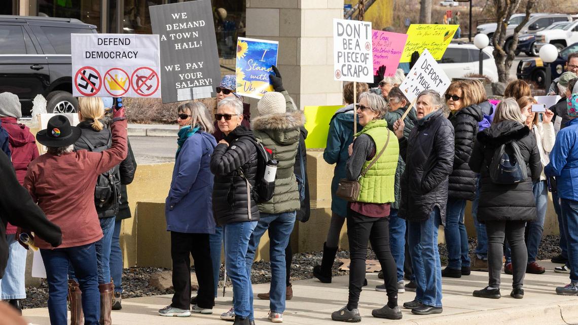 A crowd of protesters carrying anti Trump and DOGE signs line the sidewalk perimeter around The Riverside Hotel in this March file photo.