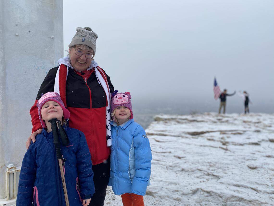 Mitzi Cheldelin, center, poses with 5-year-old granddaughters Glacin Cunningham, left, and Ripley Cunningham near the cross on top of Table Rock Trail on Sunday, Dec. 29, 2019. Cheldelin hiked to the top of Table Rock 100 times in 2019, the final time being Dec. 29.