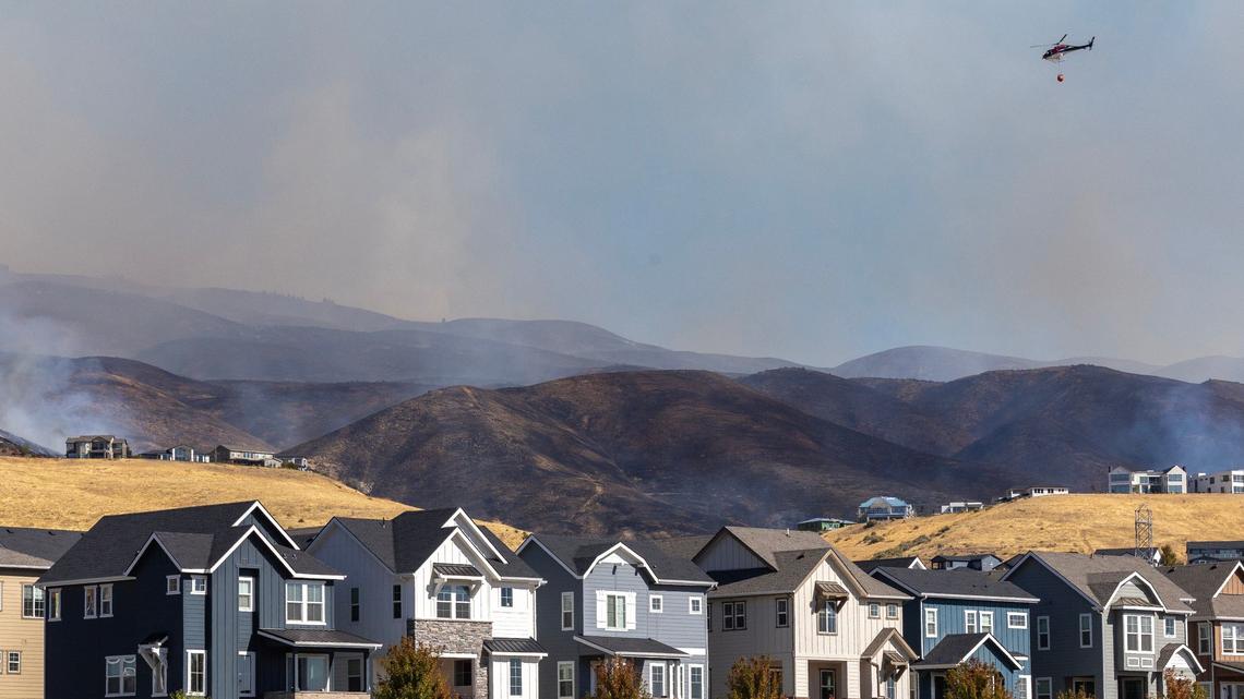 A helicopter transports water from the Boise River just north of homes in Harris Ranch.