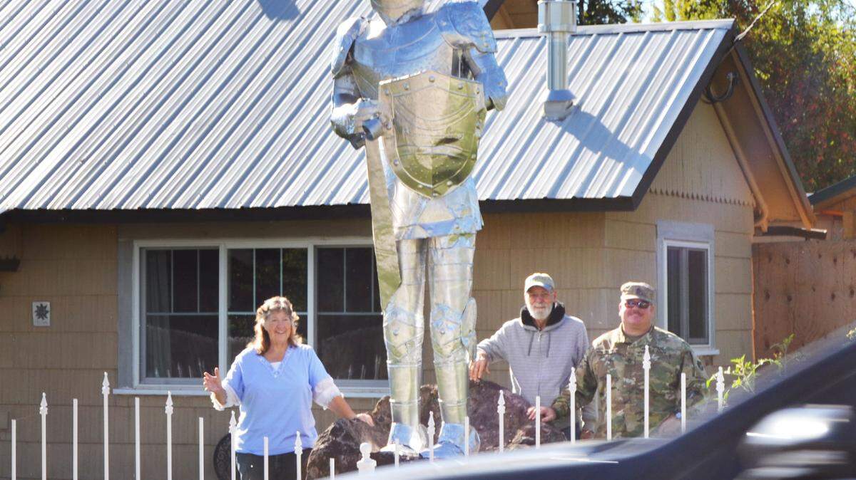 Patty Hamm, Jim Bemrose and Billy Moyer wave at passing cars as they stand next to a 10-foot-tall knightÕs armor made of tin that is believed to be a movie prop from the 1980s. ÒThe Tin Man,Ó as he came to be called, served as a protector of sorts for dozens of foster children who came to live with the Hamms.