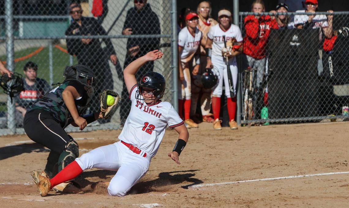 Owyhee freshman McKenna Schab slides into home plate, beating a throw to Eagle catcher Emry Woods in the 5A District Three softball championship game Friday at Borah High.