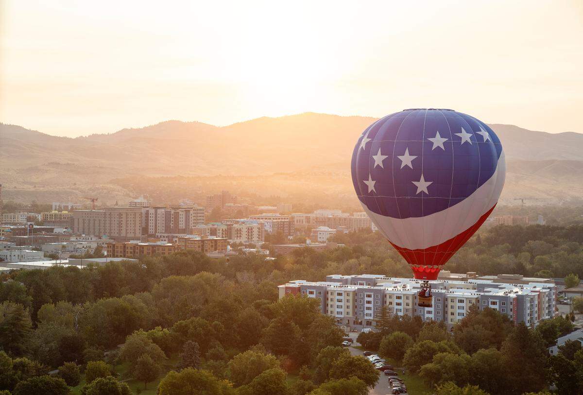 The rising sun illuminates Boise’s foothills as the hot air balloon Liberty Belle flies over Ann Morrison Park during the Spirit of Boise Balloon Classic.