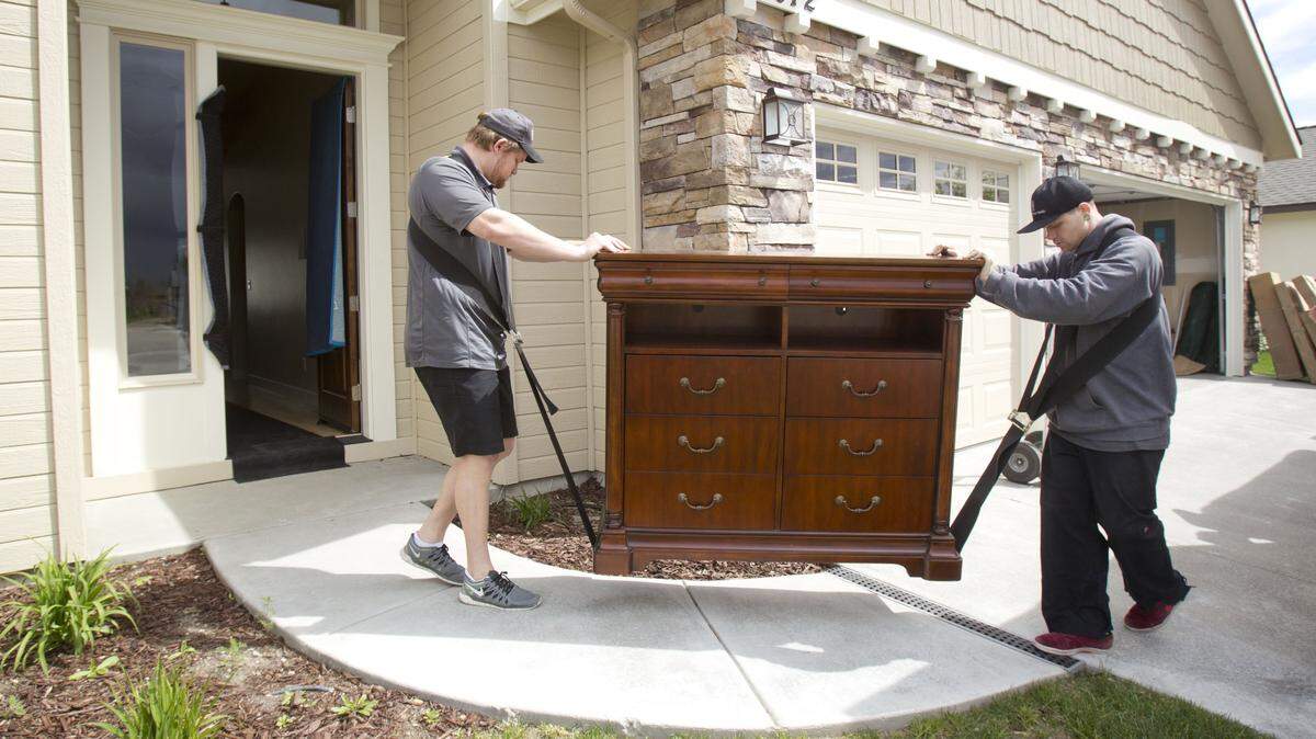 Workers for Two Men and a Truck unload a portable storage unit into a new home in Nampa.