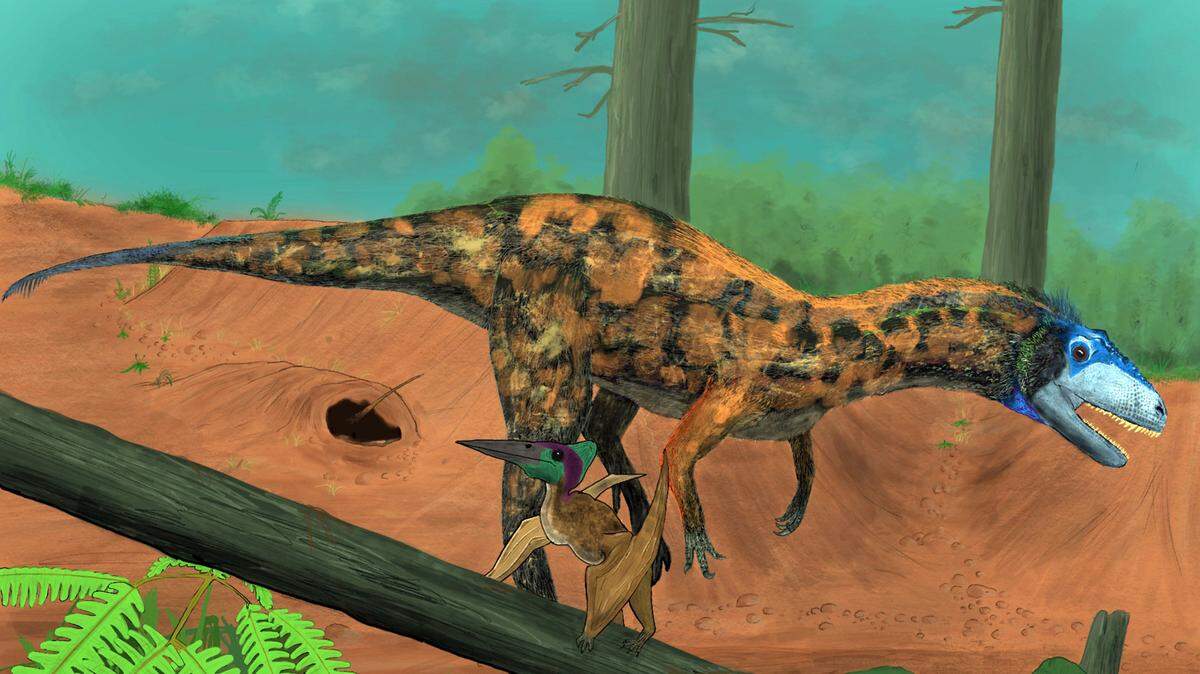 The image shows an artistic reconstruction of a brown and green tyrannosaur with a blue head.