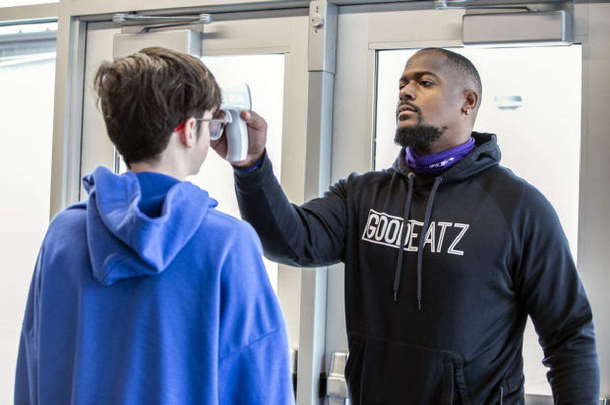 Armand Nance, “student guru” at Elevate Academy, checks students temperatures as they enter the building.