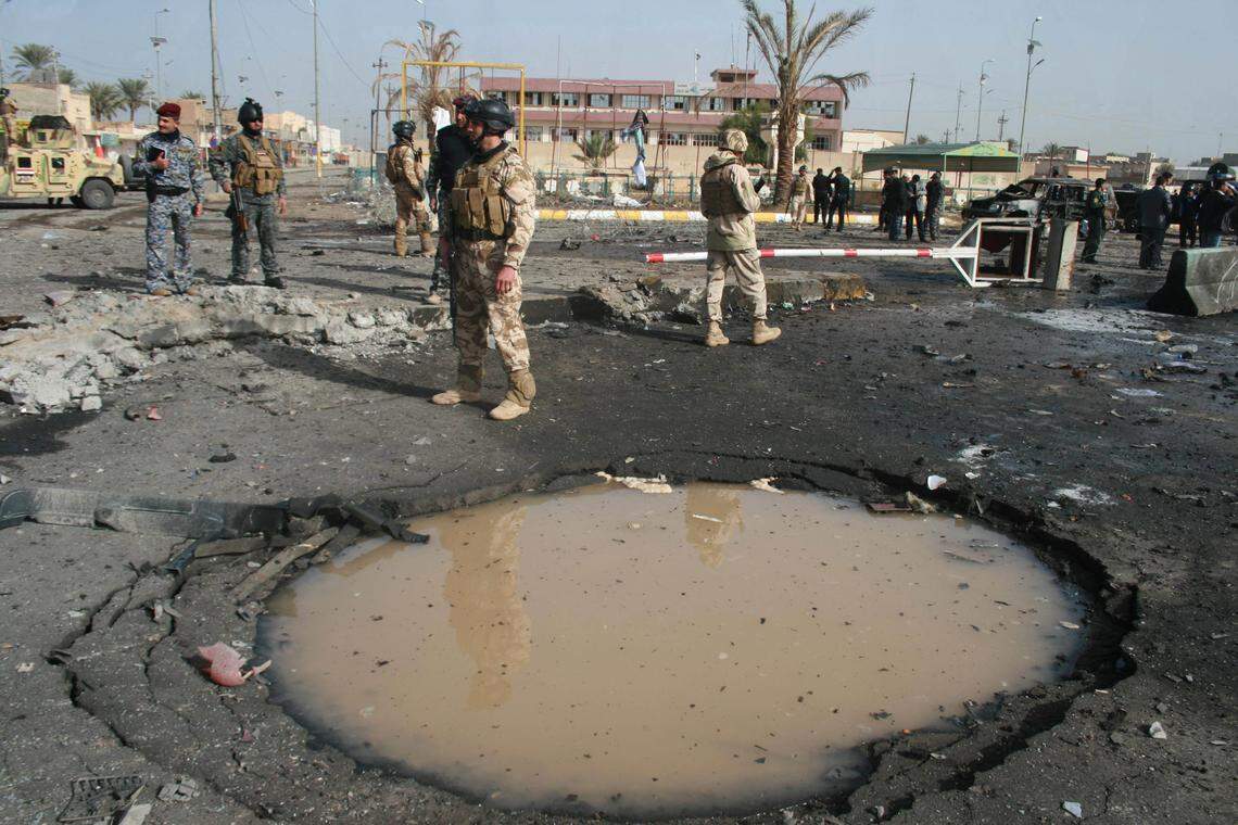 Iraqi security forces inspect a crater caused by a car bomb attack in Ramadi, 70 miles (115 kilometers) west of Baghdad, Iraq, Sunday, Dec. 12, 2010. A suicide bomber blew up his car Sunday outside government offices in a province west of the Iraqi capital, killing and wounding scores of people, including women and elderly people waiting to collect welfare checks, officials said. (AP Photo