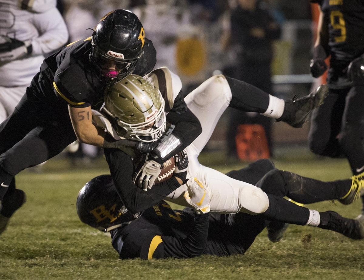 Bishop Kelly’s Dan Marlow, left, and Will Grasser drop Vallivue’s Carson Child in last week’s semifinal.