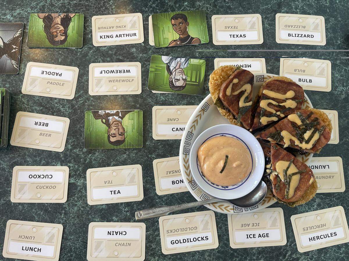 MUSUB-I-DAHO dish from Chits and Chats sit on top of an ongoing game of Codenames: Duet.