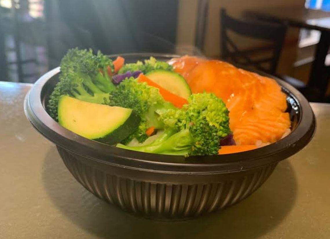 Steam rises from vegetables in a salmon bowl.