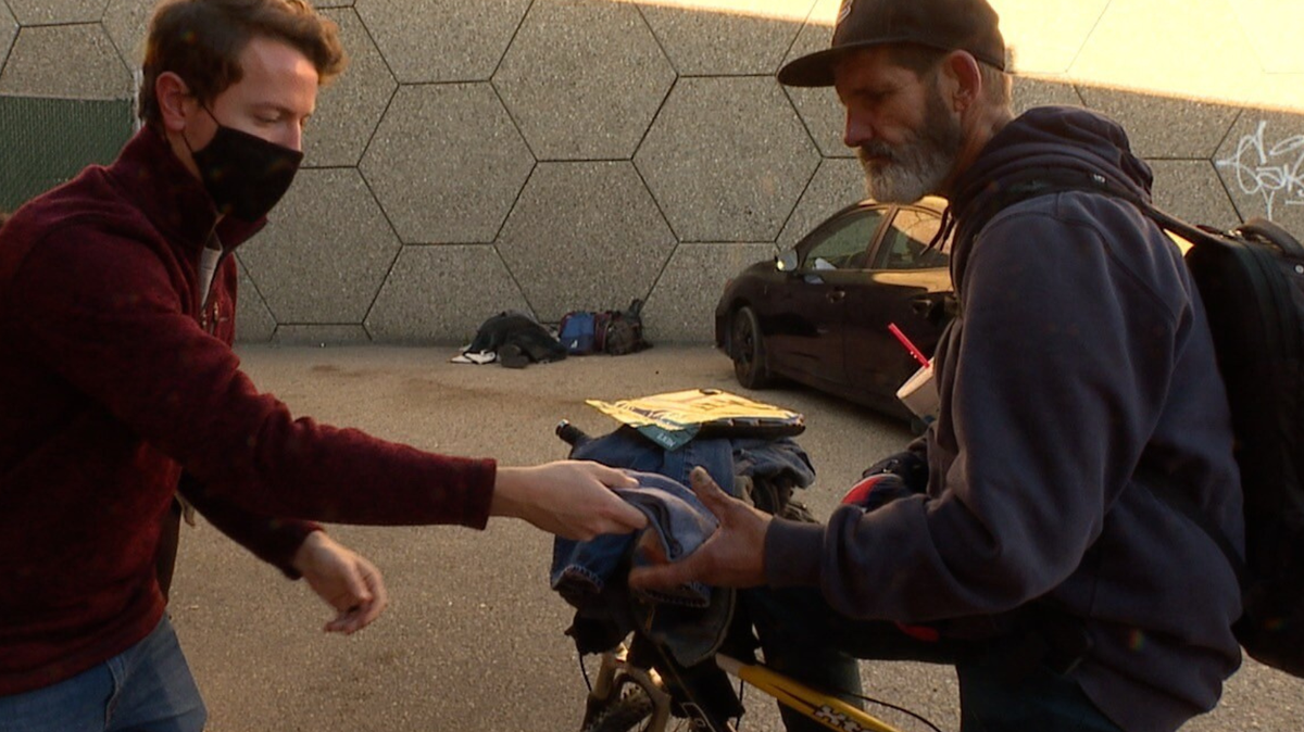 Garrett Kalt, left, of CATCH, gives winter gear to a man experiencing homelessness.