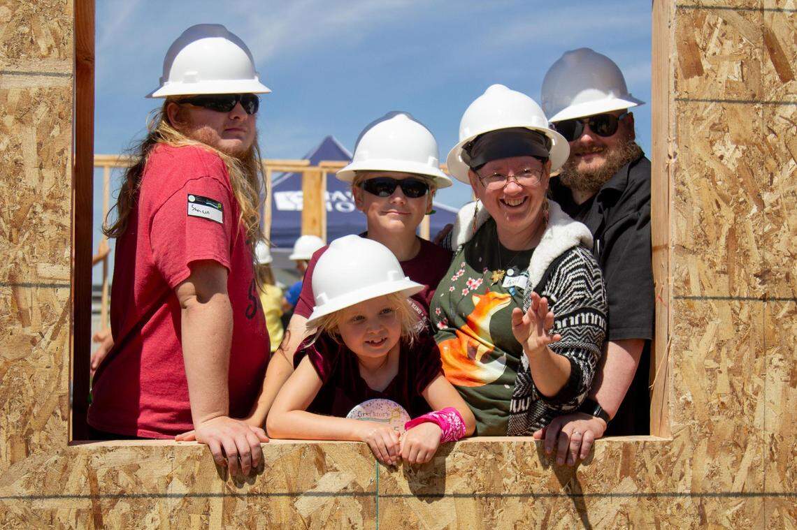 April and Christopher Kuper and their three children, 8-year-old Jesse, 13-year-old Corey and 15-year-old Shawn, look out of the window frame of their new home on June 14, 2023.