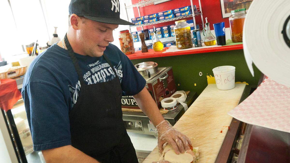 In this 2011 photo, owner Stephen Beltucci builds a signature New York-style deli sandwich at Uncle Giuseppe’s near the intersection of Glenwood and State streets.
