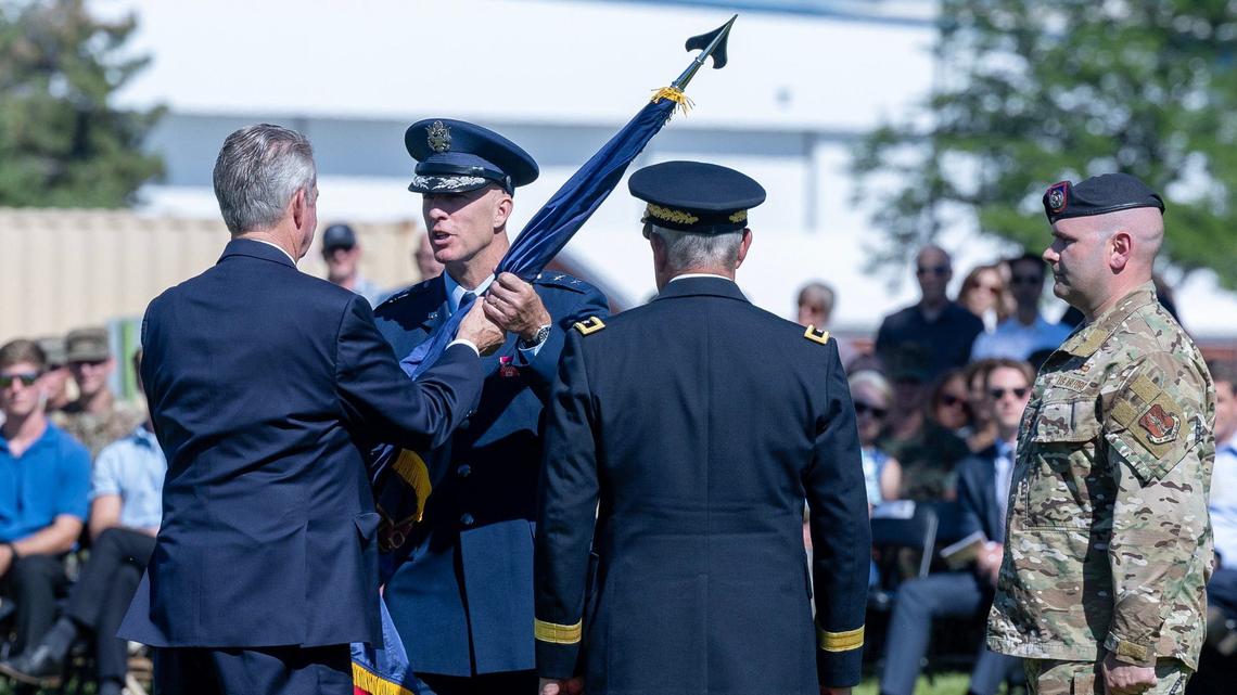 Idaho Gov. Brad Little hands over the National Guard flag from outgoing commander, Michael J. Garshak, to the incoming commander, Maj. Gen. Timothy J. Donnellan, during a ceremony at Gowen Field.