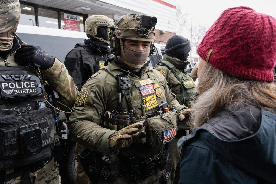 A woman confronts US Border Patrol agents near US Border Patrol commander Gregory Bovino's car at a gas station in Minneapolis, Minnesota on January 21, 2026. The Pentagon has ordered 1,500 US soldiers to prepare for a possible deployment to a state roiled by unrest over an immigration crackdown, US media reported on January 18. The reported preparations come days after President Donald Trump threatened to invoke the Insurrection Act, which enables use of the military to suppress "armed rebellion" or "domestic violence" -- although a day later he said there was no immediate need for it. (Photo by ROBERTO SCHMIDT / AFP via Getty Images)