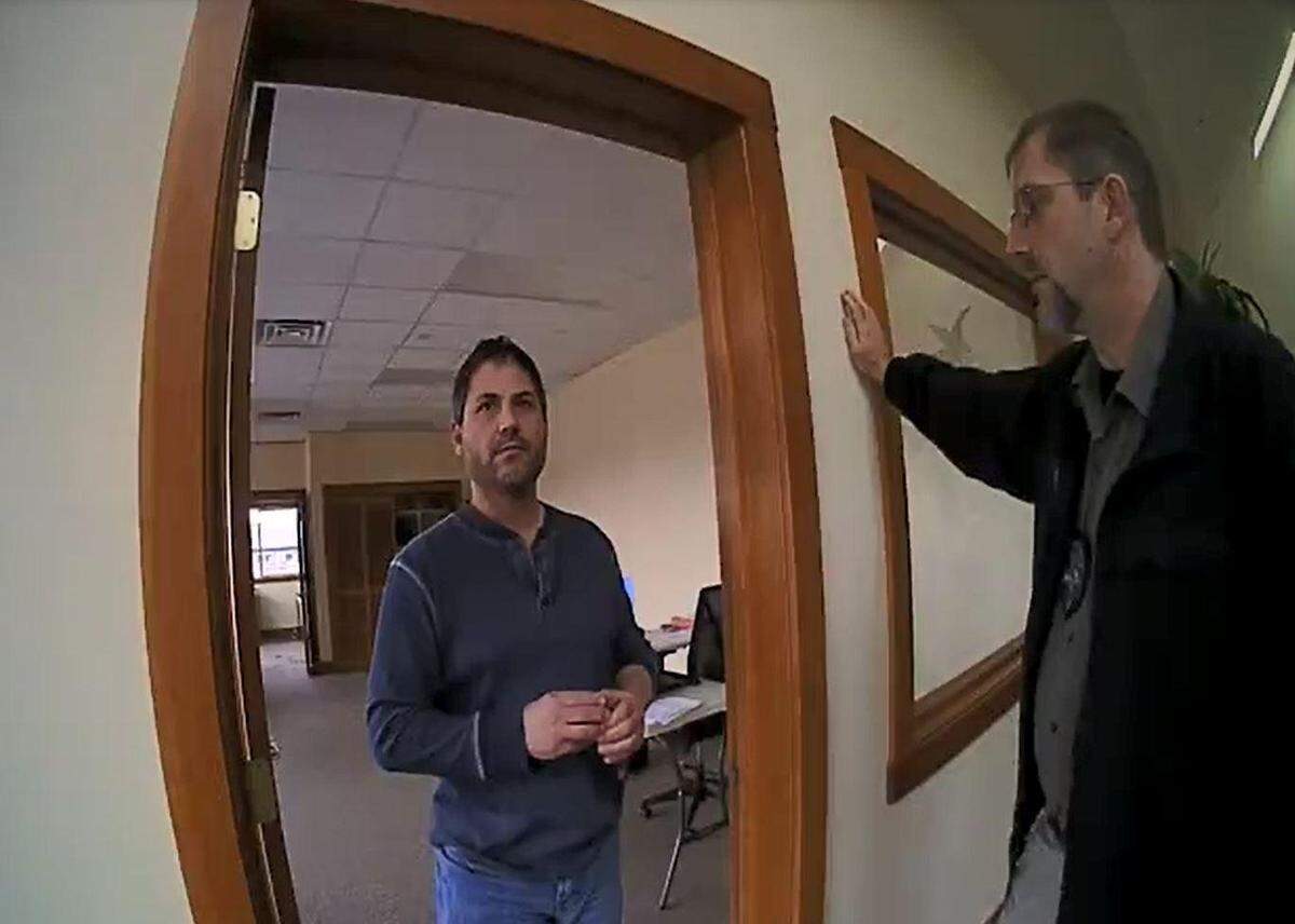 Scott Rhodes, left, speaks with Sandpoint police Officer Spencer Smith and Detective Mike Aerni, right, on Dec. 1, 2017. Police say Rhodes was captured on surveillance video the previous day distributing racist propaganda CDs at Sandpoint High School.