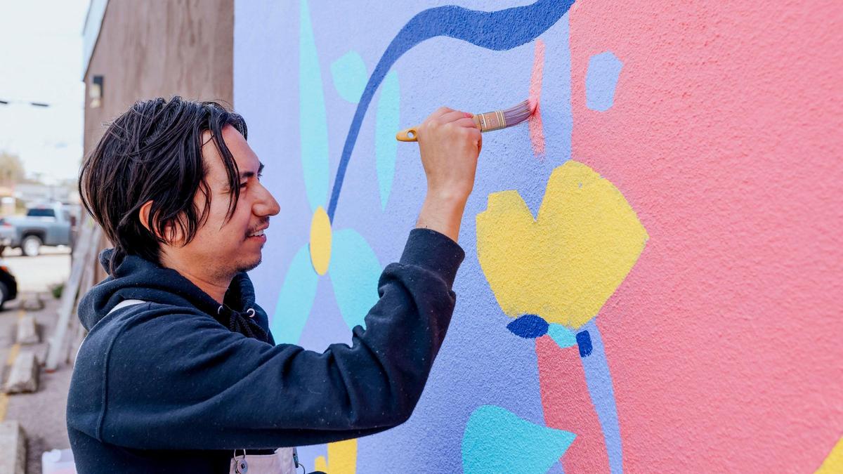 Artist Miguel Almedia at his mural in Garden City.
