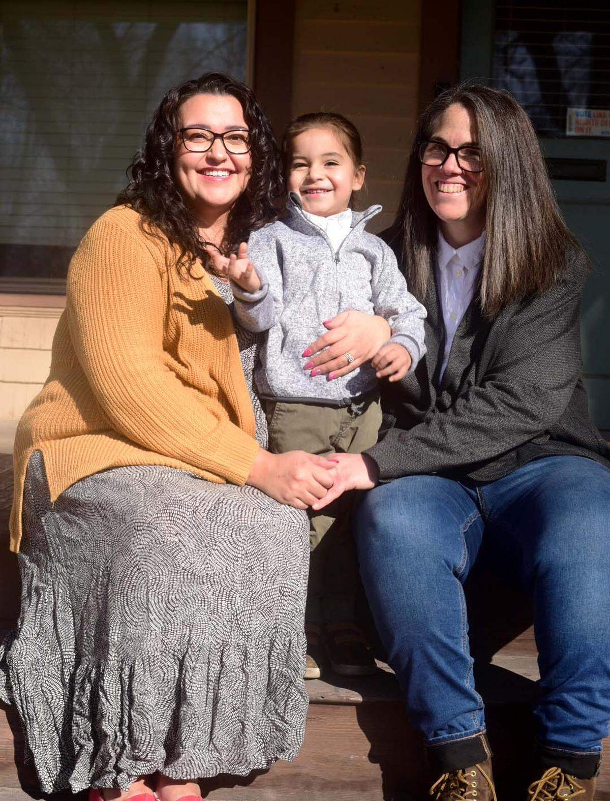 Chelsea Gaona Lincoln (left) and her wife Van Beechler (right) hold their child Rolly outside of their Caldwell home. Gaona Lincoln was one of four women who sued Idaho over its state law, which denied pregnant people the right to their living will. 