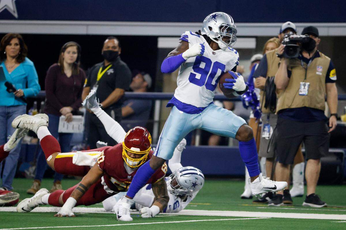 Dallas Cowboys defensive end Demarcus Lawrence breaks a tackle on the way to the end zone for a touchdown after intercepting a pass by Washington Football Team quarterback Taylor Heinicke on Sunday in Arlington, Texas.