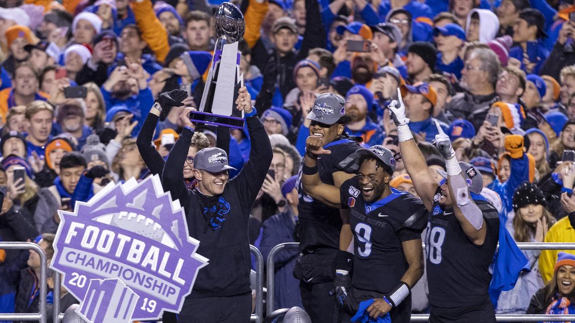 Boise State football coach Bryan Harsin holds the Mountain West championship trophy in December 2019 with offensive and defensive MVPs Jaylon Henderson and Sonatane Lui following a 31-10 win over Hawaii.